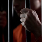 Epstein Probe DEAD, Feds Say “Move Along” Person holding metal bars in dark setting
