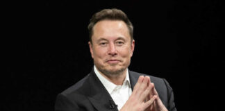 Man in suit clasping hands against black background