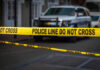 Yellow police tape in front of blurred vehicles