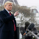 Man gesturing near microphones outside a building