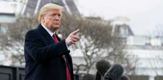 Man gesturing near microphones outside a building