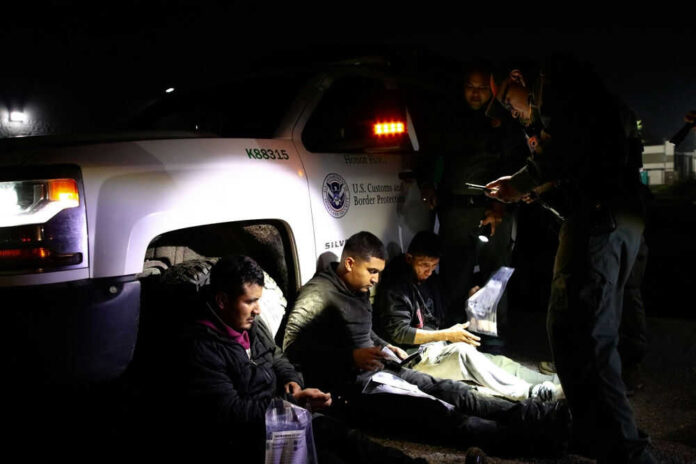 Officials interacting with seated individuals at nighttime outdoors