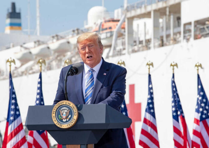 Man speaking at podium with flag background