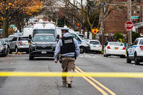 shutterstock_1867892029.jpg Law enforcement officer walking towards a crime scene marked by police tape
