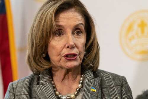 Nancy Pelosi speaking at a press event with a Ukrainian flag pin