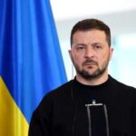 A political leader standing in front of a Ukrainian flag during a press conference