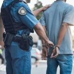 Police officer handcuffing a suspect in a street setting