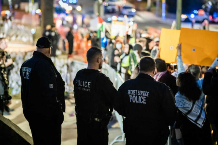 Police officers monitor a crowd with signs