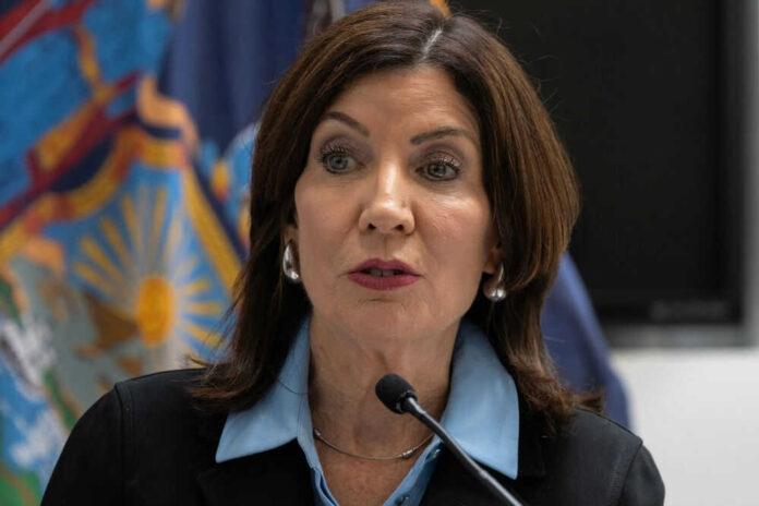 Woman speaking at a podium with flags behind