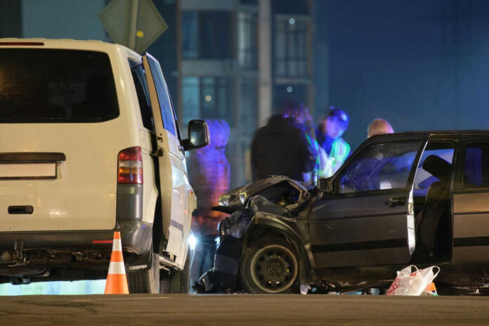 Two cars crashed at night with people nearby