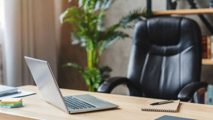 Office desk with laptop and black leather chair
