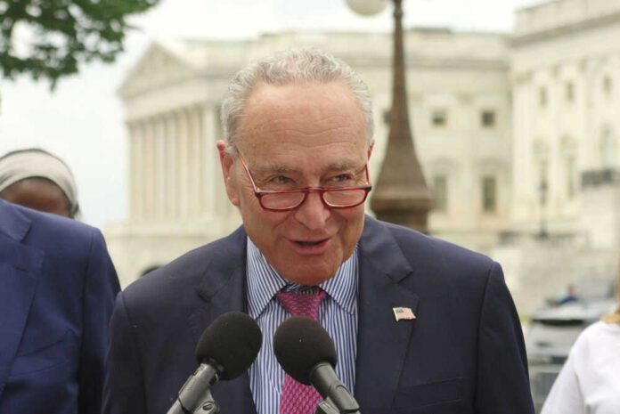 Man speaking at outdoor event wearing suit and glasses