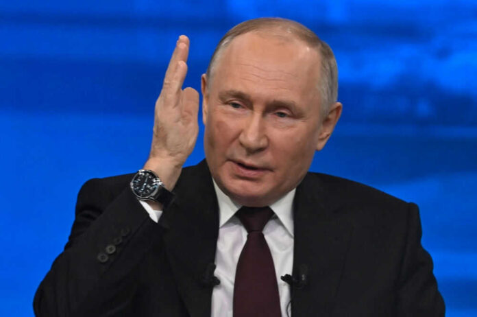Man in suit gesturing with hand speaking on stage