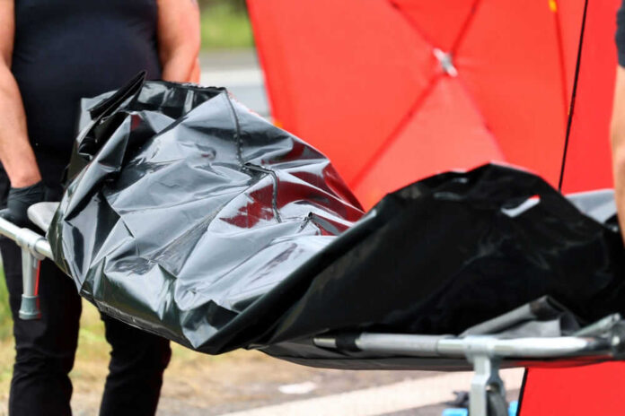 Person carrying body bag on stretcher outdoors