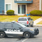 Police car parked near residential building officers nearby