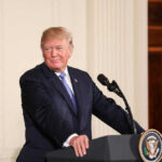 Person standing at podium with presidential seal