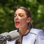 Person speaking into microphones outdoors in natural setting