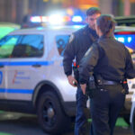 Police officers standing near NYPD vehicles at night