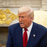 Man in a suit speaking in an ornate room