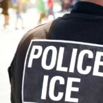 Police officers back with ICE label visible
