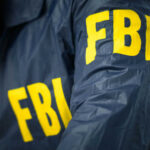 Person wearing blue jacket with FBI lettering