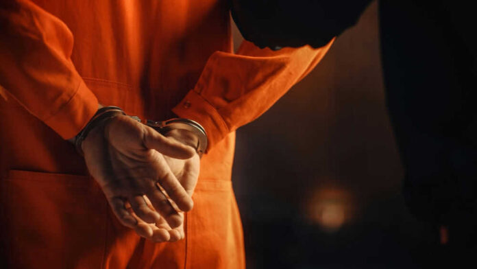 Person in orange jumpsuit wearing handcuffs behind back