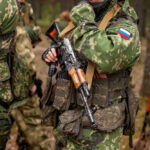 Soldiers in camouflage gear holding rifles in forest