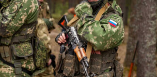 Soldiers in camouflage gear holding rifles in forest