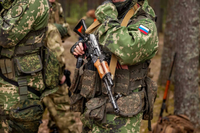 Soldiers in camouflage gear holding rifles in forest