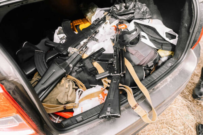 Guns and bags inside car trunk on grass