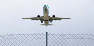 Airplane taking off above a wire fence
