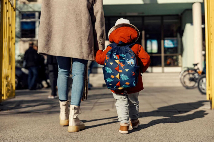 Adult and child walking towards a school building