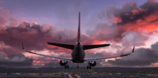 Airplane approaching airport runway at sunset sky