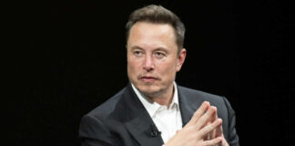 Man in black suit sitting with hands clasped