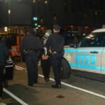 Police officers detain a person near NYPD vehicle