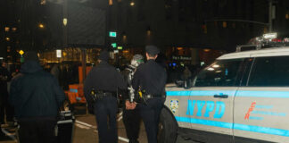 Police officers detain a person near NYPD vehicle