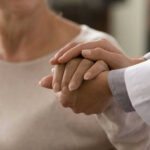 Doctor holding patients hand in comforting gesture