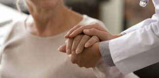 Doctor holding patients hand in comforting gesture
