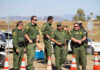 Group of law enforcement officers in green uniforms standing near traffic cones